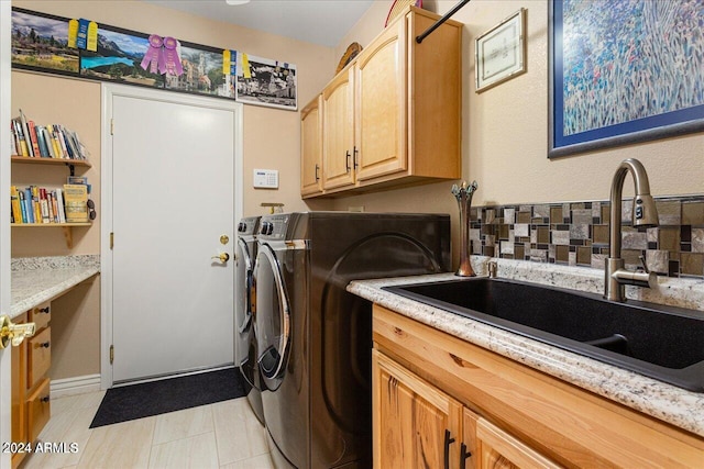 laundry area with cabinets, separate washer and dryer, and sink