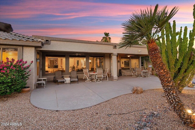 back house at dusk featuring a patio area