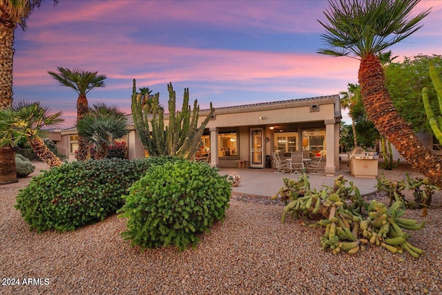 back house at dusk with a patio area and exterior kitchen