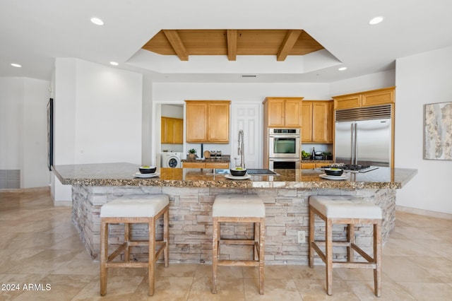 kitchen with a kitchen bar, stainless steel appliances, a large island, and sink