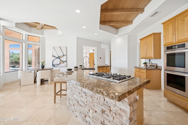 kitchen featuring wood ceiling, stainless steel appliances, sink, beam ceiling, and a center island with sink