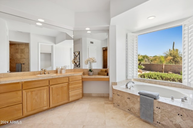 bathroom featuring tile patterned flooring, vanity, a healthy amount of sunlight, and tiled tub