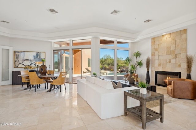 living room featuring a tile fireplace and a tray ceiling