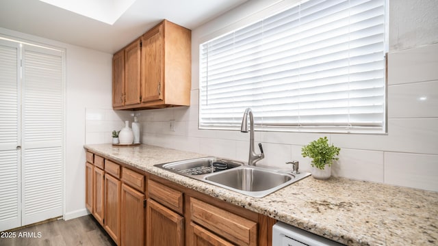 kitchen with tasteful backsplash, light wood-style flooring, light countertops, and a sink