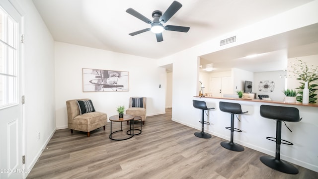 living area with visible vents, plenty of natural light, baseboards, and wood finished floors