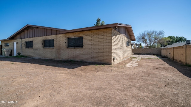 view of home's exterior with brick siding, board and batten siding, and fence