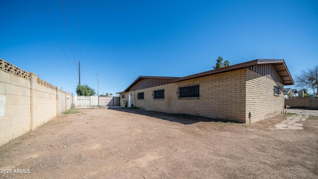 back of property with brick siding, board and batten siding, and fence