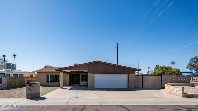 view of front of home featuring brick siding, an attached garage, fence, driveway, and a gate