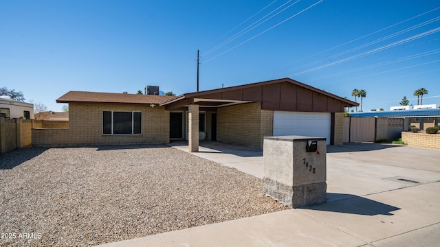 ranch-style house featuring fence, brick siding, concrete driveway, a garage, and board and batten siding