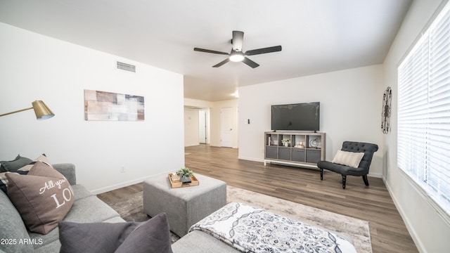 living area featuring visible vents, baseboards, a ceiling fan, and wood finished floors