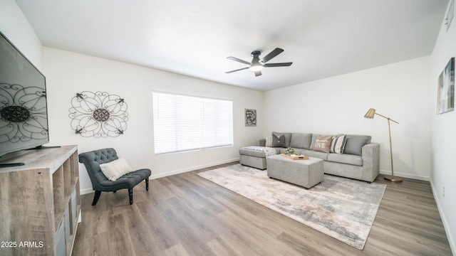 living room with ceiling fan, baseboards, and wood finished floors