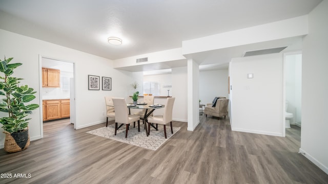 dining room featuring wood finished floors, visible vents, and baseboards