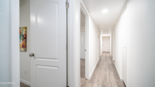 hall with baseboards and light wood finished floors