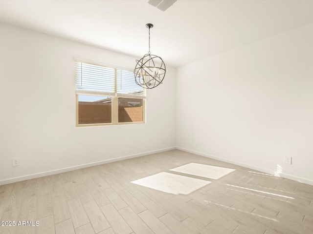 spare room with light wood-type flooring and a notable chandelier