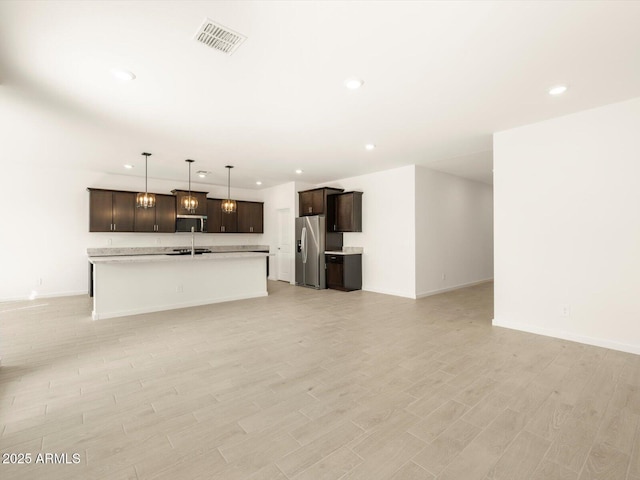 kitchen with stainless steel appliances, sink, a center island with sink, and dark brown cabinetry