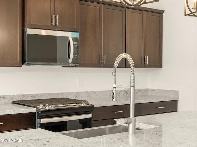 kitchen with light stone counters, stainless steel appliances, and dark brown cabinetry