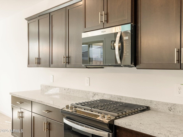 kitchen with light stone counters, dark brown cabinetry, and appliances with stainless steel finishes