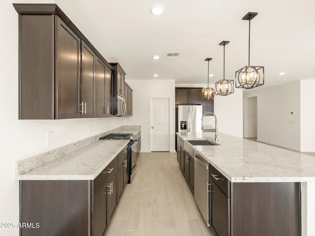 kitchen with sink, light stone counters, decorative light fixtures, dark brown cabinets, and stainless steel appliances