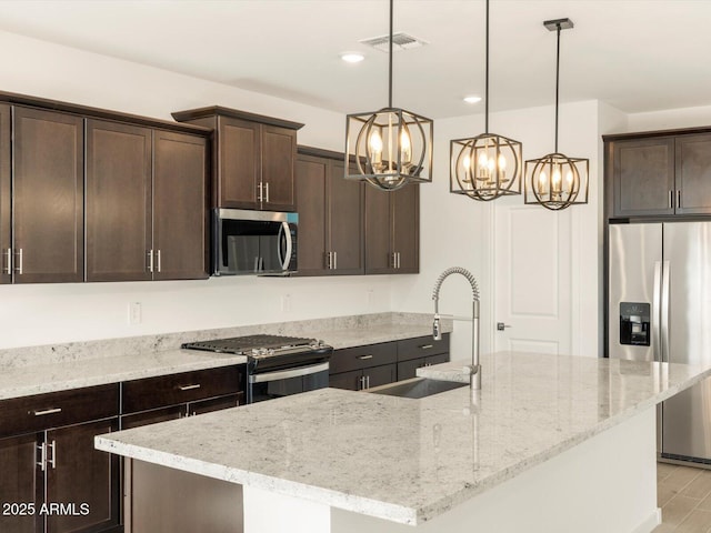 kitchen featuring light stone counters, stainless steel appliances, and a kitchen island with sink