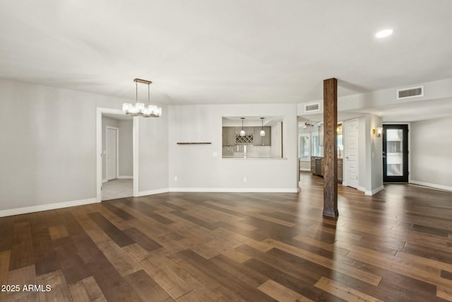 unfurnished living room featuring dark wood-type flooring and a chandelier