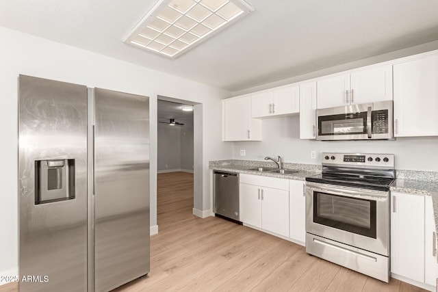 kitchen with sink, white cabinetry, light stone countertops, and appliances with stainless steel finishes