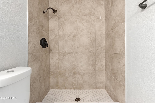 bathroom featuring tiled shower and toilet