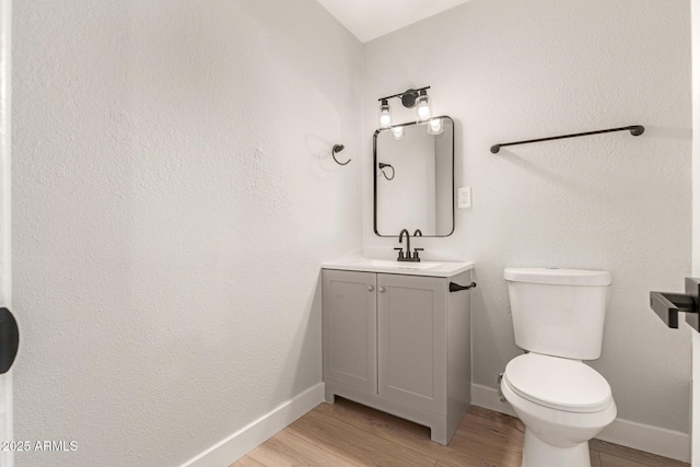 bathroom featuring wood-type flooring, toilet, and vanity