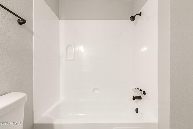 bathroom featuring shower / bathtub combination and toilet