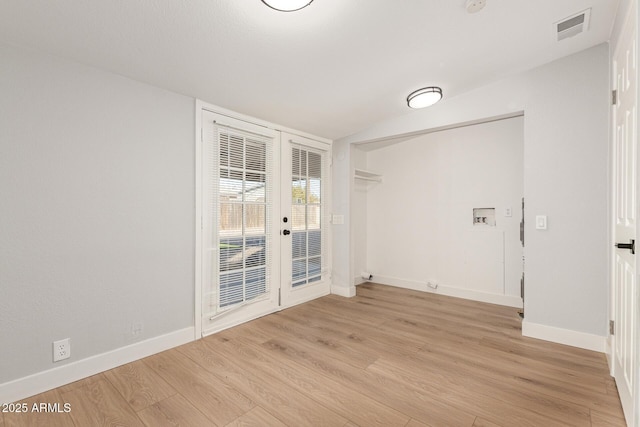 spare room with light hardwood / wood-style floors, french doors, and vaulted ceiling