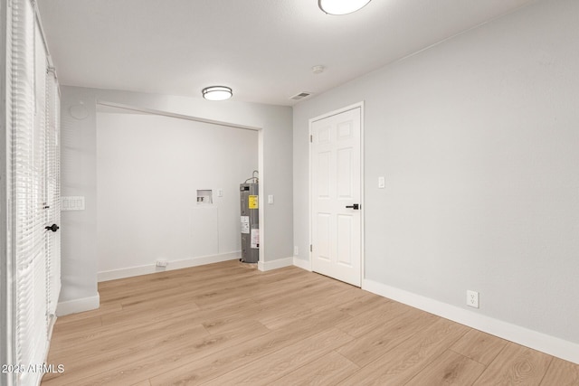 laundry room with water heater, light hardwood / wood-style flooring, and washer hookup