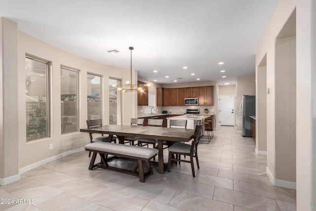 dining space featuring a notable chandelier, light tile patterned floors, and sink