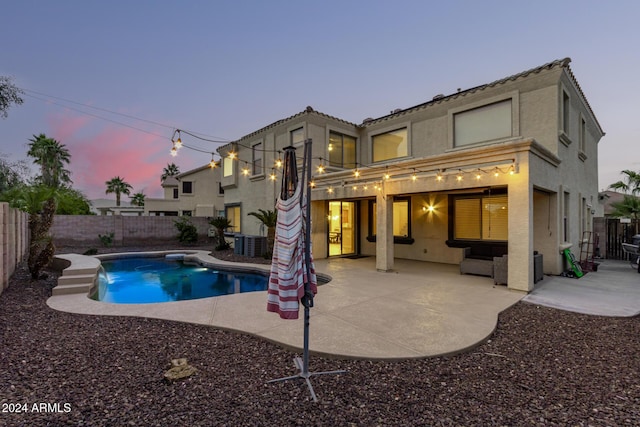 pool at dusk featuring central air condition unit and a patio