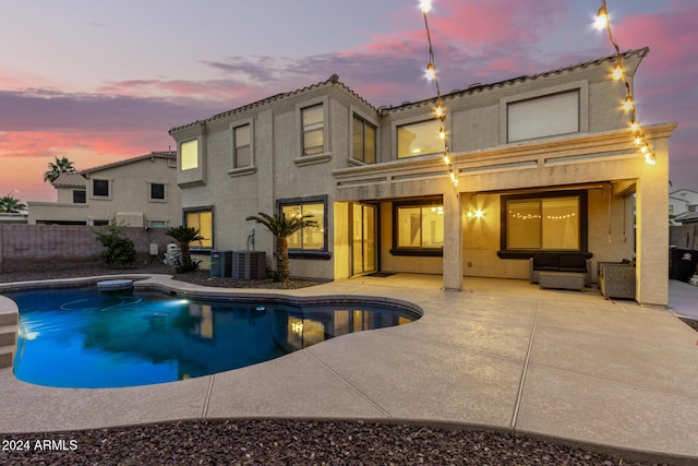 pool at dusk featuring a patio area and central AC