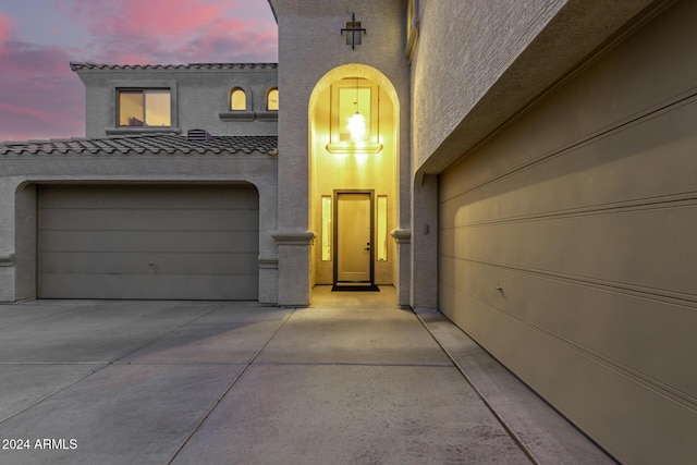 exterior entry at dusk featuring a garage