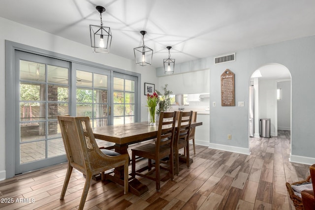 dining room with arched walkways, baseboards, visible vents, and wood tiled floor