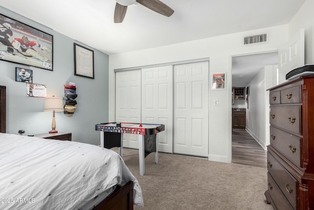 bedroom with ceiling fan, light colored carpet, visible vents, baseboards, and a closet