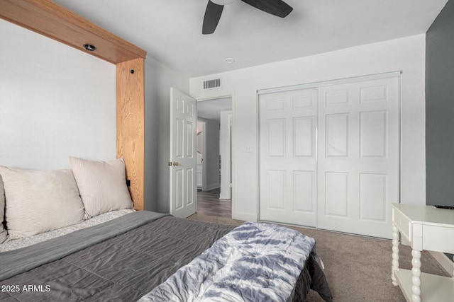 bedroom with a closet, dark carpet, visible vents, and a ceiling fan