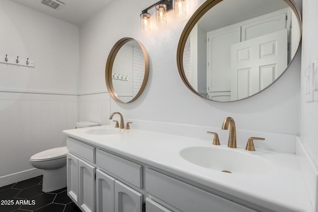 bathroom with wainscoting, visible vents, a sink, and toilet