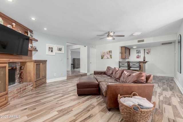 living area featuring a brick fireplace, visible vents, and light wood-style floors