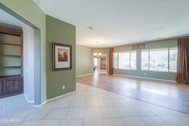 empty room featuring a chandelier and light wood-type flooring