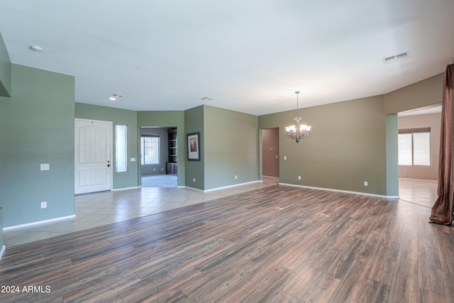 empty room with an inviting chandelier and hardwood / wood-style flooring