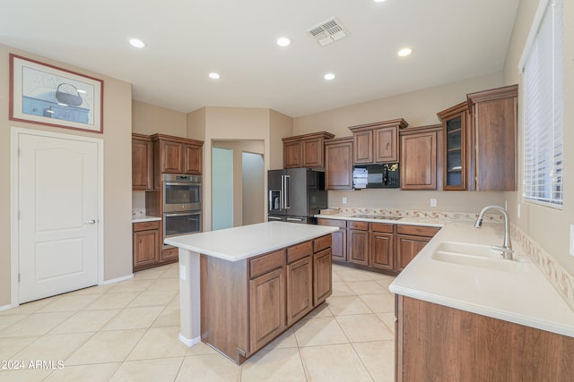 kitchen with light tile patterned floors, stainless steel appliances, sink, and a kitchen island