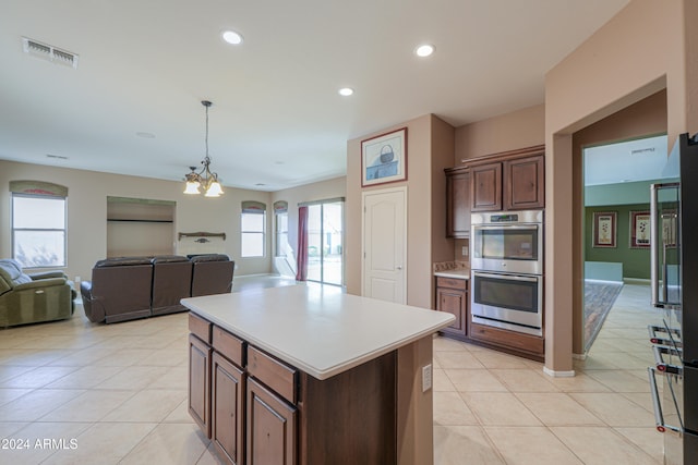 kitchen featuring a healthy amount of sunlight, an inviting chandelier, a kitchen island, and stainless steel double oven