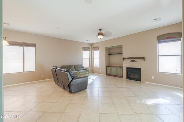 living room with light tile patterned flooring, a tiled fireplace, and ceiling fan