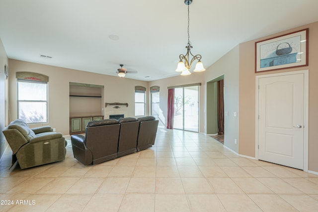 living room featuring a healthy amount of sunlight, light tile patterned floors, and ceiling fan with notable chandelier