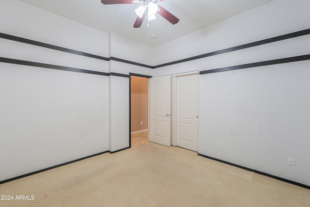 unfurnished bedroom featuring light colored carpet, a closet, and ceiling fan