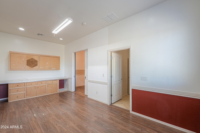 interior space with light hardwood / wood-style floors, light brown cabinets, and built in desk