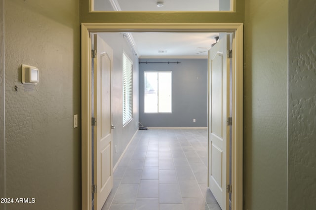 corridor featuring crown molding and light tile patterned flooring