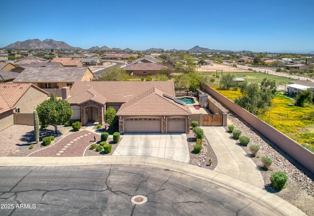 view of front of property with fence, a tile roof, driveway, a garage, and a mountain view