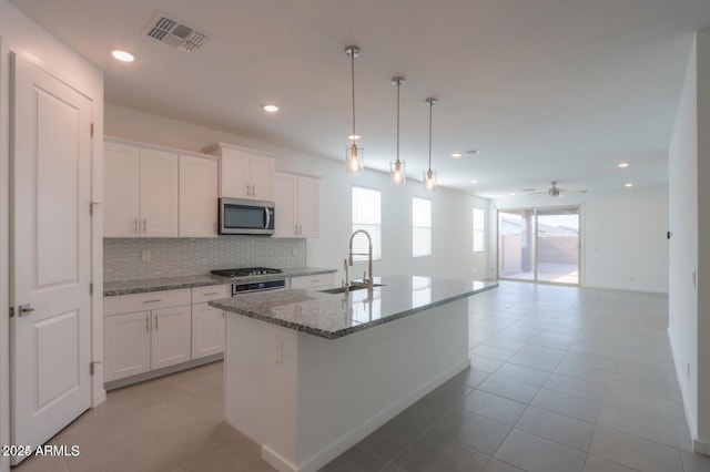 kitchen with sink, white cabinetry, light stone counters, hanging light fixtures, and a kitchen island with sink